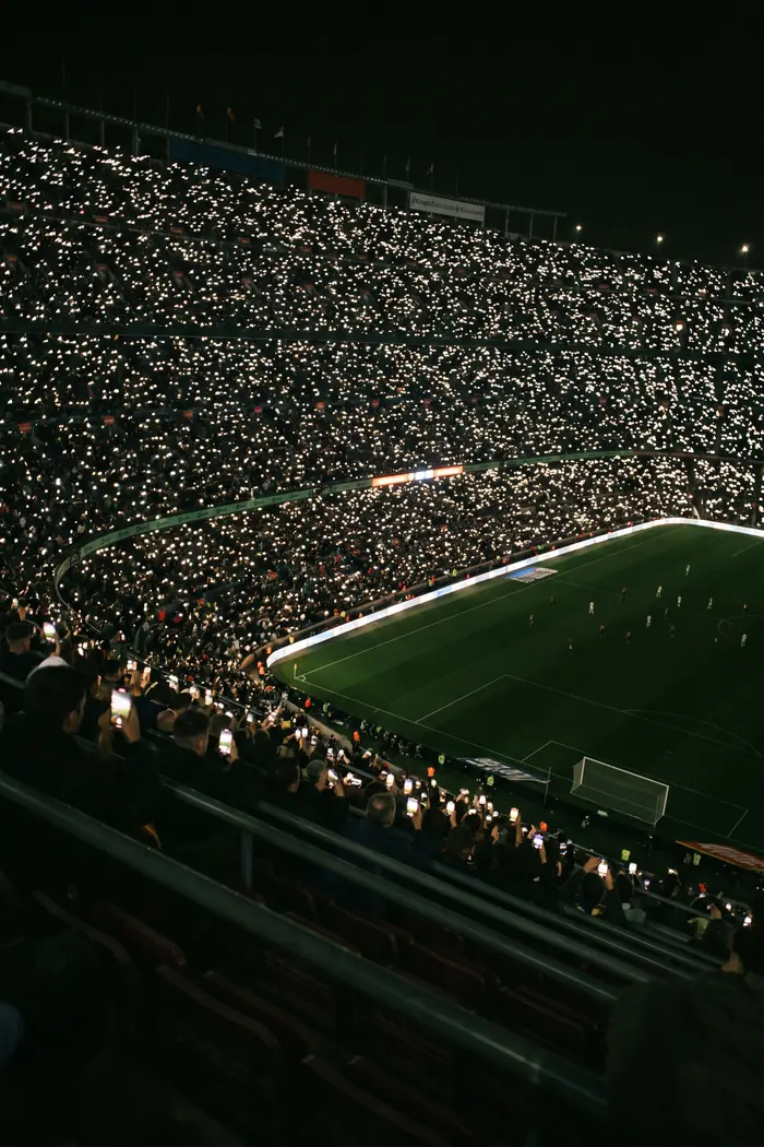 A full stadium at night with thousands of phone screens lit in the crowd