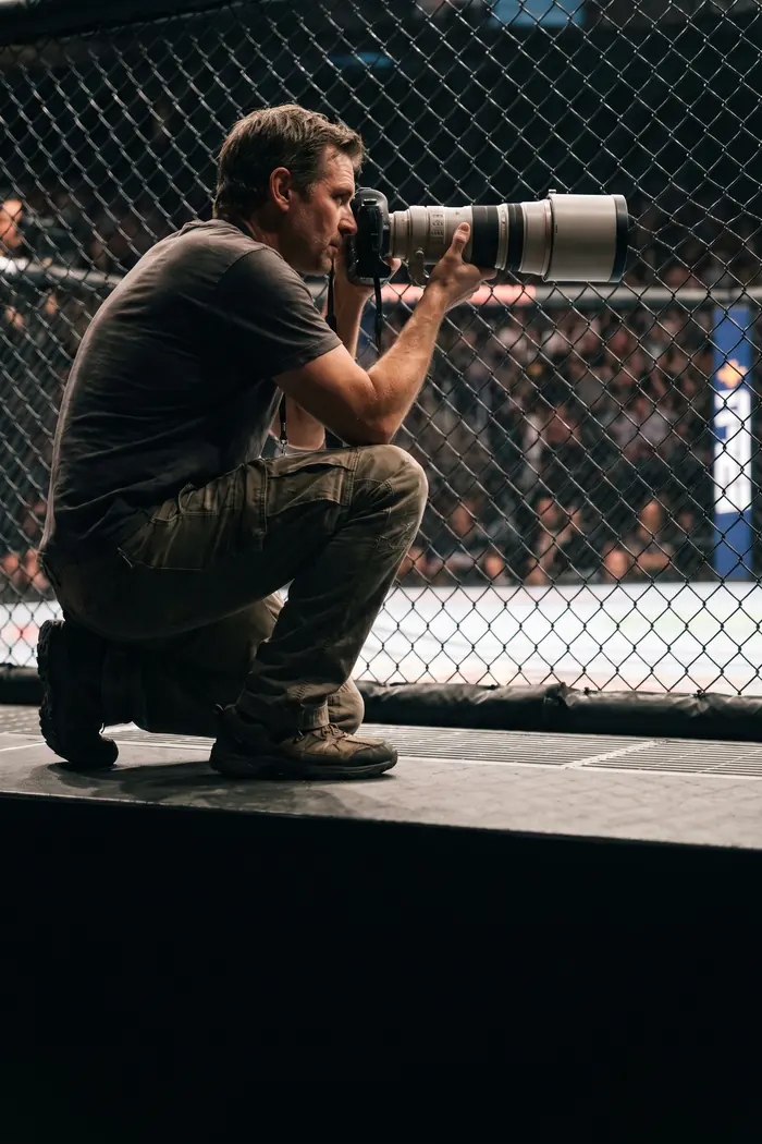 A photographer shooting cage-side at a fight night